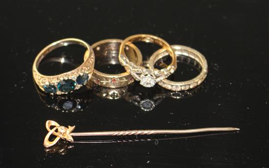 A 1960s 9ct gold and three stone sapphire ring with diamond chip spacers, three other dress rings and a stick pin.